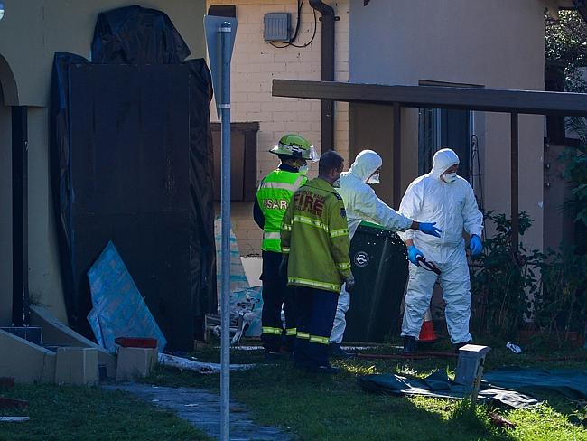 Fire and Rescue officers, wearing protective anti-asbestos gear, help NSW Ambulance crews