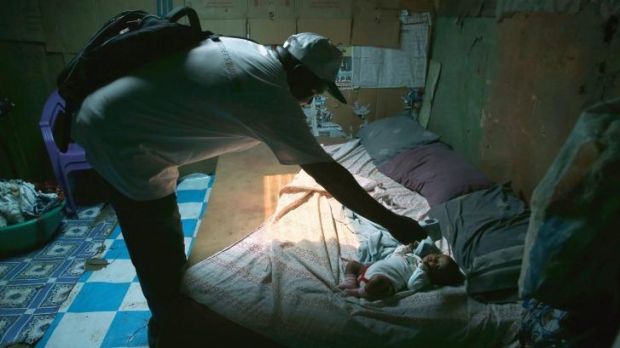 On guard: Ebola tracing co-ordinator John Mbayoh checks a baby's temperature in Monrovia, Liberia.