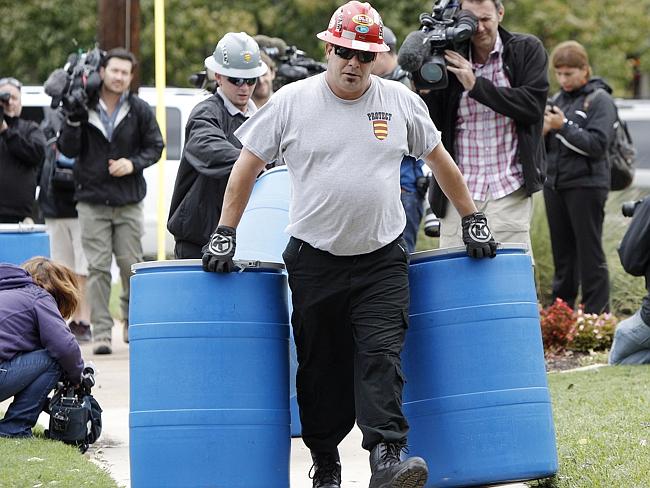 Protective measures ... an environmental worker moves disposal barrels to a staging area 