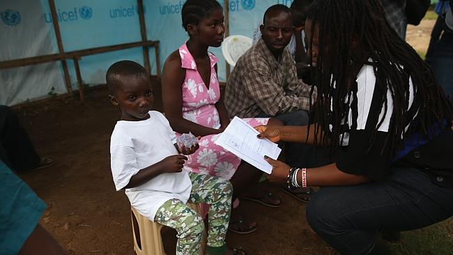 Tragic ... Ebola survivor Abrahim Quota, 5, is handed a letter confirming his recovery fr