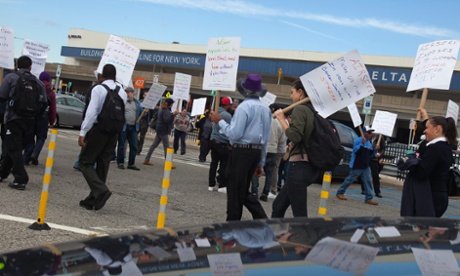 Protesters hold up signs during a one-day strike by airline cabin cleaners demanding more protection in the fight against Ebola, at LaGuardia Airport.