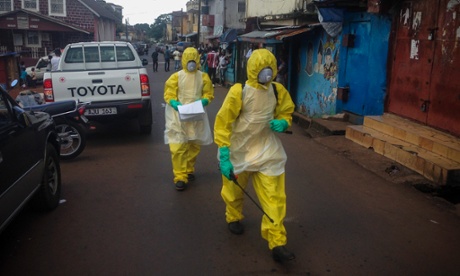 Health workers walk to pick up a four-month-old baby victim of Ebola in central Freetown.