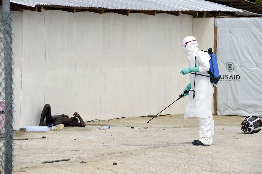 A health worker stands near a man suspected of suffering from the Ebola virus as he lies on the ground naked after he was admitted to Island Hospital in Monrovia on Oct. 2, 2014.