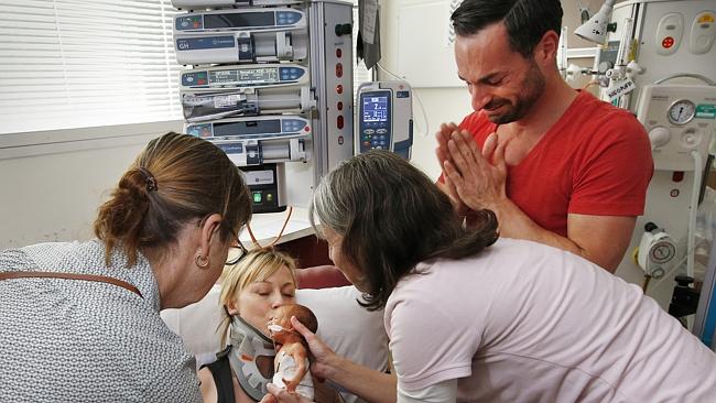 Nurses hold baby Ava to get a kiss from mum Michelle as an emotional dad Alex looks on. P