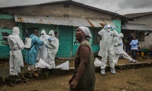 A relative grieves as a Red Cross burial team prepares to remove the body of Ofori Gweah, who died of Ebola’s telltale symptoms, in a riverside area called Rock Spring Valley in central Monrovia, Liberia. 