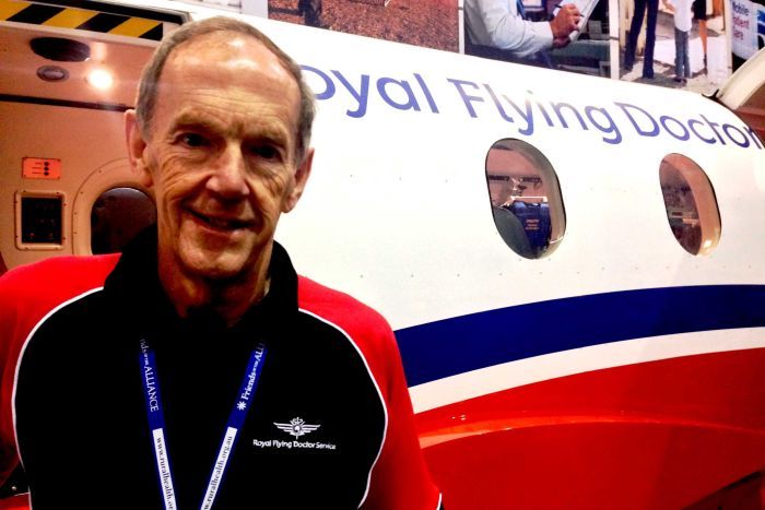 Portrait and close picture of John Setchell standing in front of a RFDS plane.