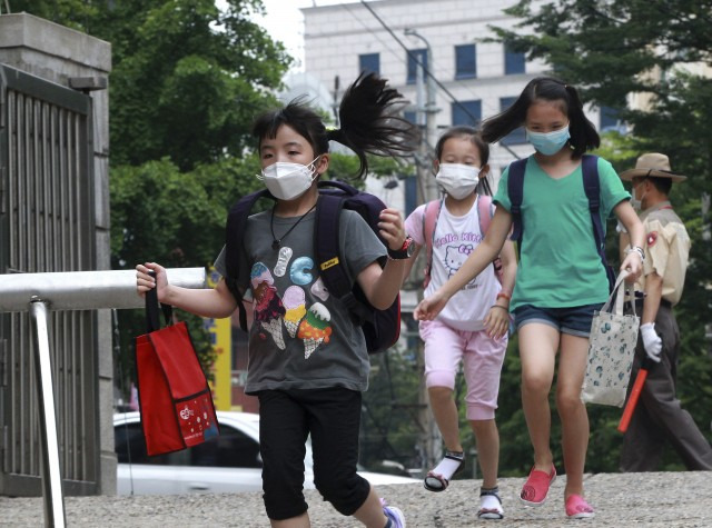 Elementary school students wear mask as a precaution against the MERS, Middle East Respiratory Syndrome, virus as they arrive at Midong elementary school in Seoul, South Korea, Monday, June 8, 2015.