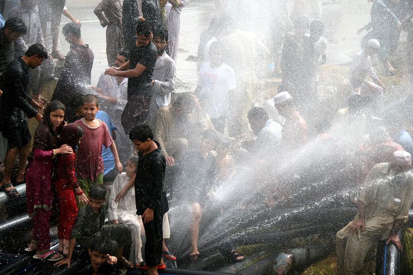 Pakistani people cool off at water supply pipelines during a heatwave in Karachi, Pakistan on June 24, 2015.