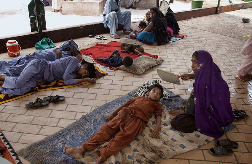 A Pakistani mother uses hand fan to her child suffering from dehydration due to sever heat while she waits her turn at a local hospital in Karachi, Pakistan.