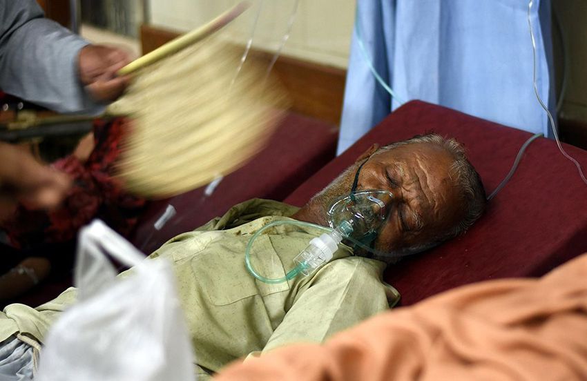 A man blows the wind to help his relative affected by the heatwave at a hospital in Karachi, Pakistan.