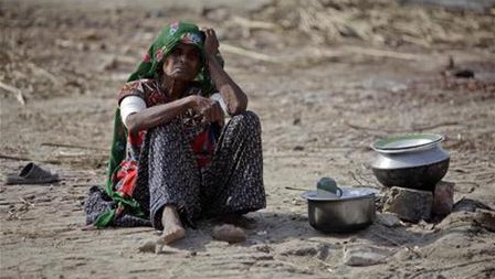 Woman, who has been displaced by floods, prepares food outside her tent after escaping from flooded village in Badin district of Pakistan's Sindh province